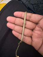 Gold chain held in a hand against a dark background